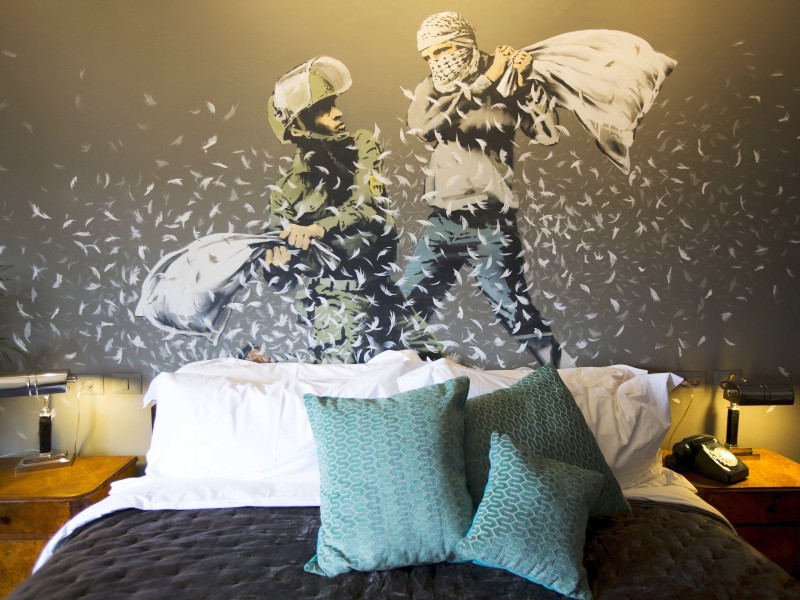 Ein Wandbild des britischen Street-Art Künstlers mit einem israelischen Soldaten und einem Palästinenser bei einer Kissenschlacht ziert ein Zimmer des „The Walled Off Hotel“.