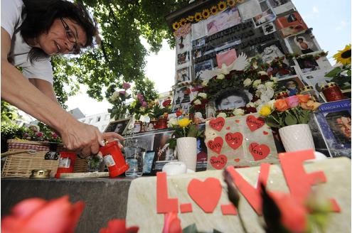 Eine Frau zündet in München an der mit Bildern behangenen Orlando-Di-Lasso-Säule am Promenadeplatz eine Kerze zum Gedenken an den Verstorbenen an.