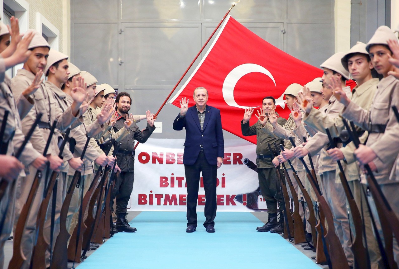 Präsident Erdogan bei einem Termin mit Angehörigen einer Nachwuchsorganisation: Die jungen Männer hatten sich in militärische Kleidung geworfen und den Präsidenten mit Rabia-Hand begrüßt.