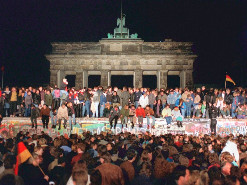 Jubelnde Menschen standen am 10. November 1989 auf der Berliner Mauer am Brandenburger Tor. Am frühen Abend des 9. November 1989 kurz vor 19 Uhr gab Zentralkomitee-Sekretär Günter Schabowski am Ende einer Pressekonferenz eher beiläufig das Inkrafttreten einer neuen Reiseregelung für DDR-Bürger bekannt.