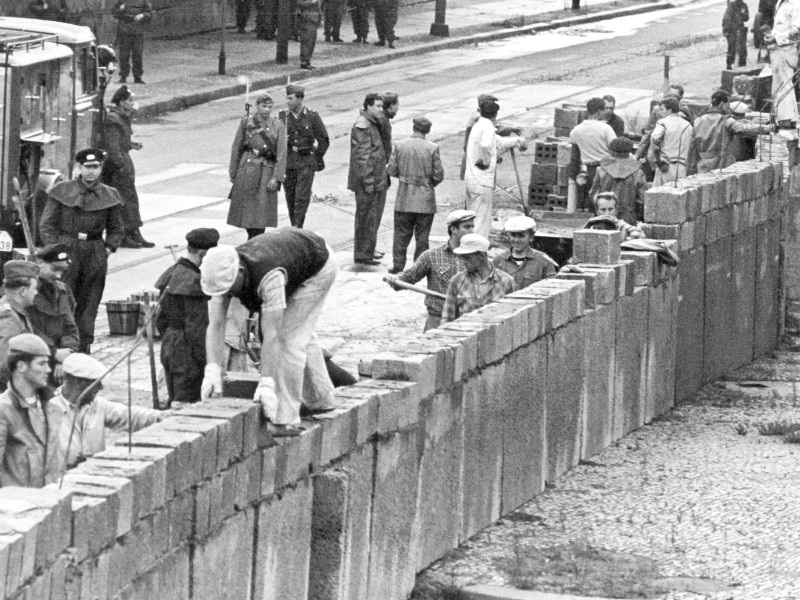 Unter der Aufsicht von bewaffneten Volkspolizisten errichtete eine Ostberliner Maurerkolonne  an der sowjetisch-amerikanischen Sektorengenze am Potsdamer Platz die Mauer. 