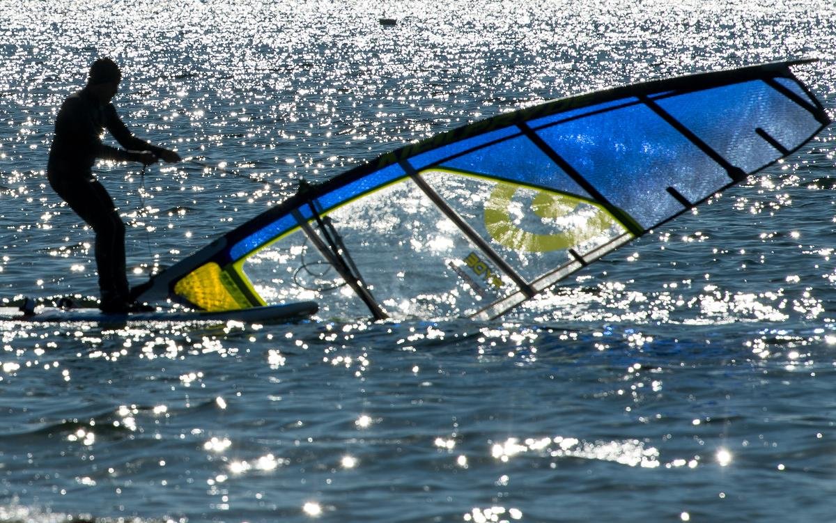 Ein Mann surft bei strahlendem Sonnenschein und sommerlichen Temperaturen auf dem Berzdorfer See bei Görlitz.