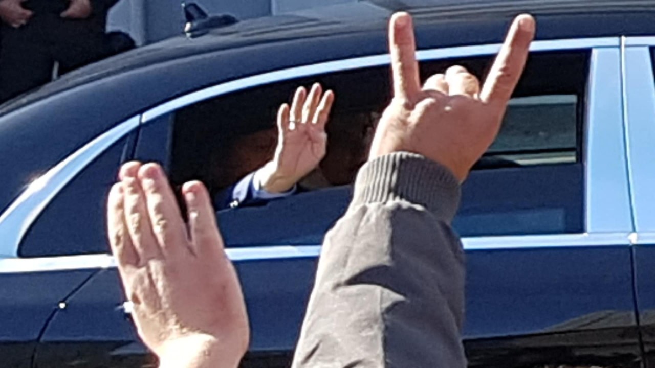 Einer seiner Anhänger zeigte Erdogan den sogenannten Wolfsgruß: Die Hand, bei der nur der Zeigefinger und der kleine Finger ausgestreckt sind, soll den Kopf eines Wolfes symbolisieren und steht für die Gruppe der rechtsextremen Grauen Wölfe. 