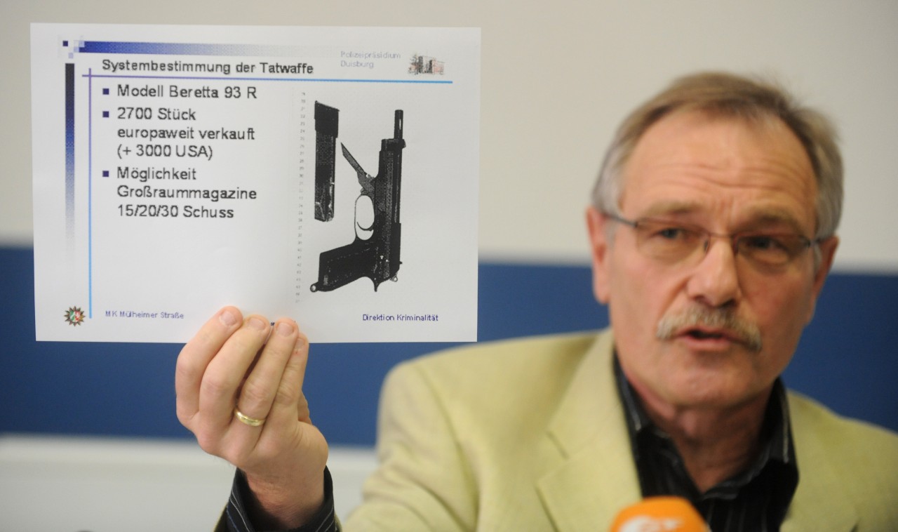 Heinz Sprenger 2009 bei einer Pressekonferenz im Polizeipräsidium Duisburg.  Er zeigt Bilder einer Waffe, mit der sechs junge Italiener brutal hingerichtet worden waren. 