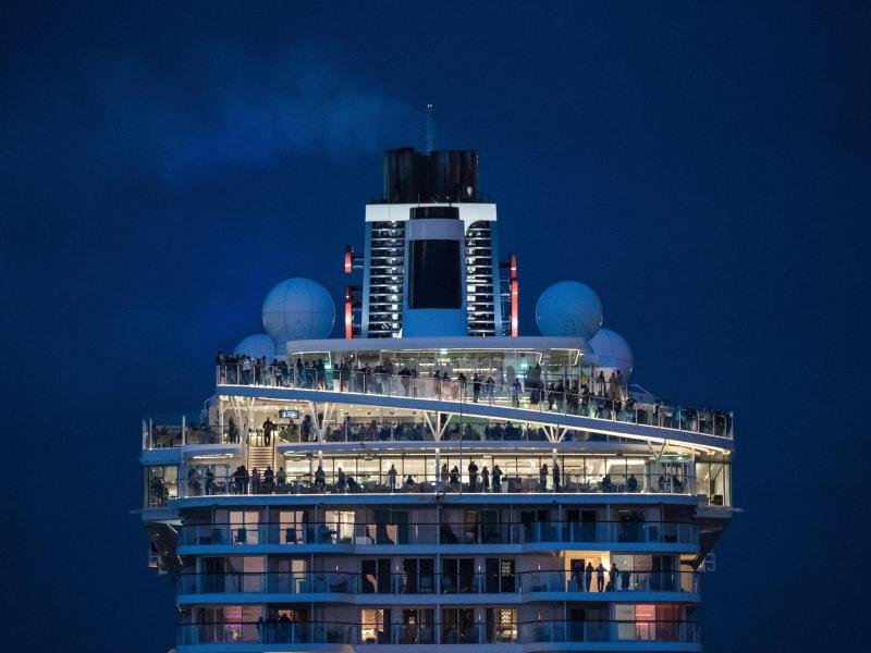 Passagiere verfolgen an Bord eines Kreuzfahrtschiffs das Auslaufen aus dem Hafen.