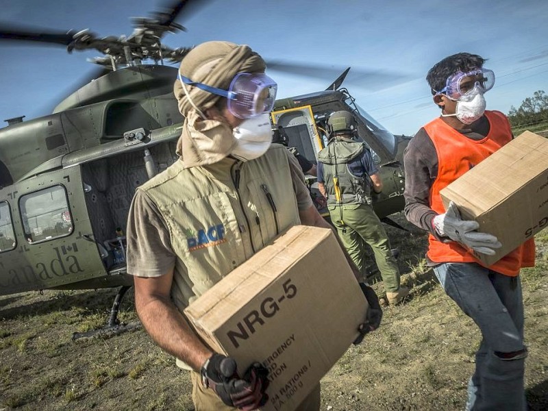 Katastrophenhelfer von ACF, einer Partnerorganisation der Kindernothilfe beladen einen Hubschrauber der Kanadischen Armee mit Nahrungspaketen. Die Notfallnahrung versorgt die Menschen für 14 Tage. Die Kanadische Armee fliegt die Hilfsgüter un unzugängliche Gebiete in den Bergen.  Die Katastrophenhelferin Lucile von ACF führt Angelika Böhling durch die Unglücksgebiete 28.11.2013 auf der Insel Panay - Phillippinen    Bild: Jakob Studnar