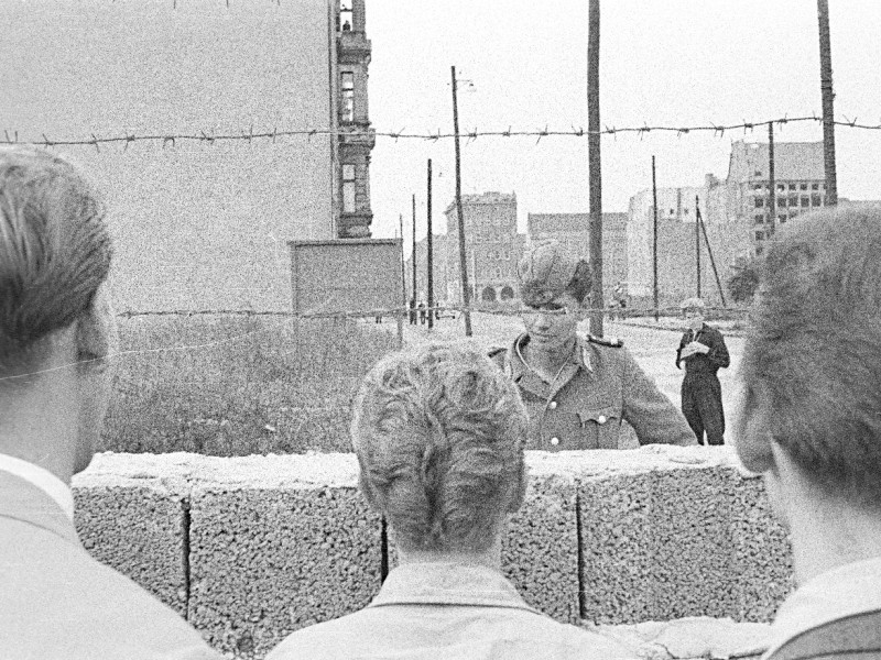 Seit dem 13. August 1961 ließ die DDR die Sektorengrenze in Berlin mit Stacheldrahtrollen sperren, alle Verbindungen zwischen Osten und Westen wurden getrennt. In den nächsten Wochen folgte der Aufbau einer Mauer aus Betonelementen, die wie hier entlang der Zimmerstraße in Kreuzberg anfangs eine geringe Höhe hat. Als Schutz vor dem Überklettern der Mauer dienten Metall-Abweiser mit Stacheldraht.