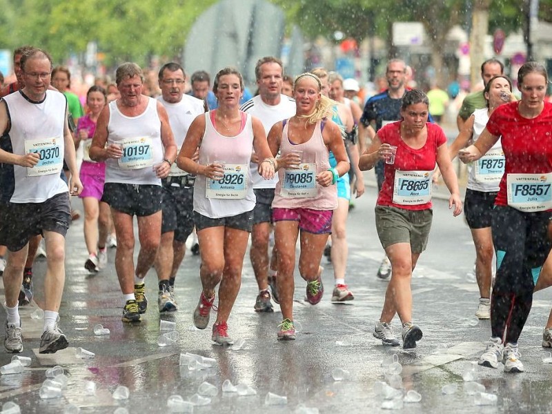 Teilnehmer des 22. Vattenfall-City-Nacht-Lauf passieren bei Temperaturen um 30 Grad Celsius auf dem Kurfürstendamm in Berlin eine Erfrischungsstation.