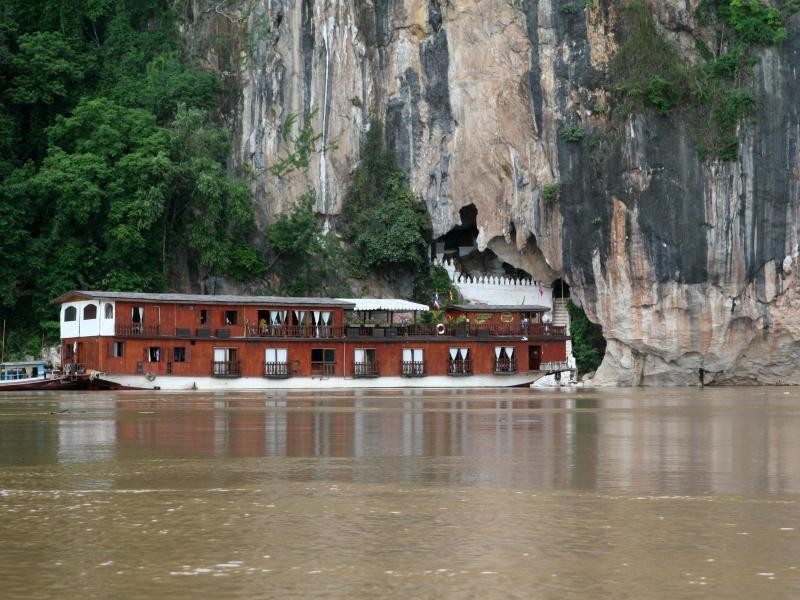 Über sumpfbraunes Wasser fährt das Schiff den Mekong hinab. An den Pak Ou Höhlen wird direkt an den Felswänden angelegt.