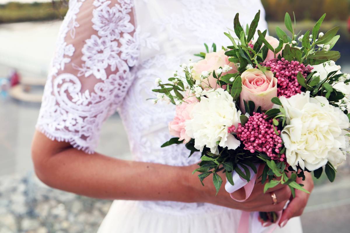 Hochzeit: Eine Braut trägt einen Strauß Blumen