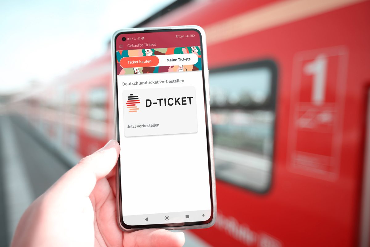 Deutschlandticket auf Handy mit Bahn im Hintergrund