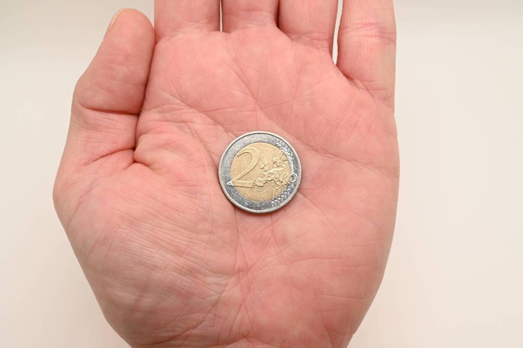 Eine 2-Euro-Münze liegt in der geöffneten Hand eines Menschen.
