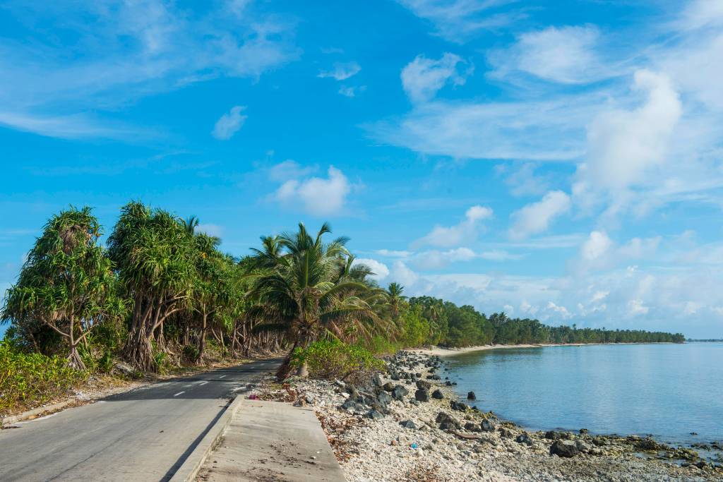 Knapp am Ufer verläuft eine asphaltierte Straße nur wenige Zentimeter über Meeresspiegel auf Tuvalu.