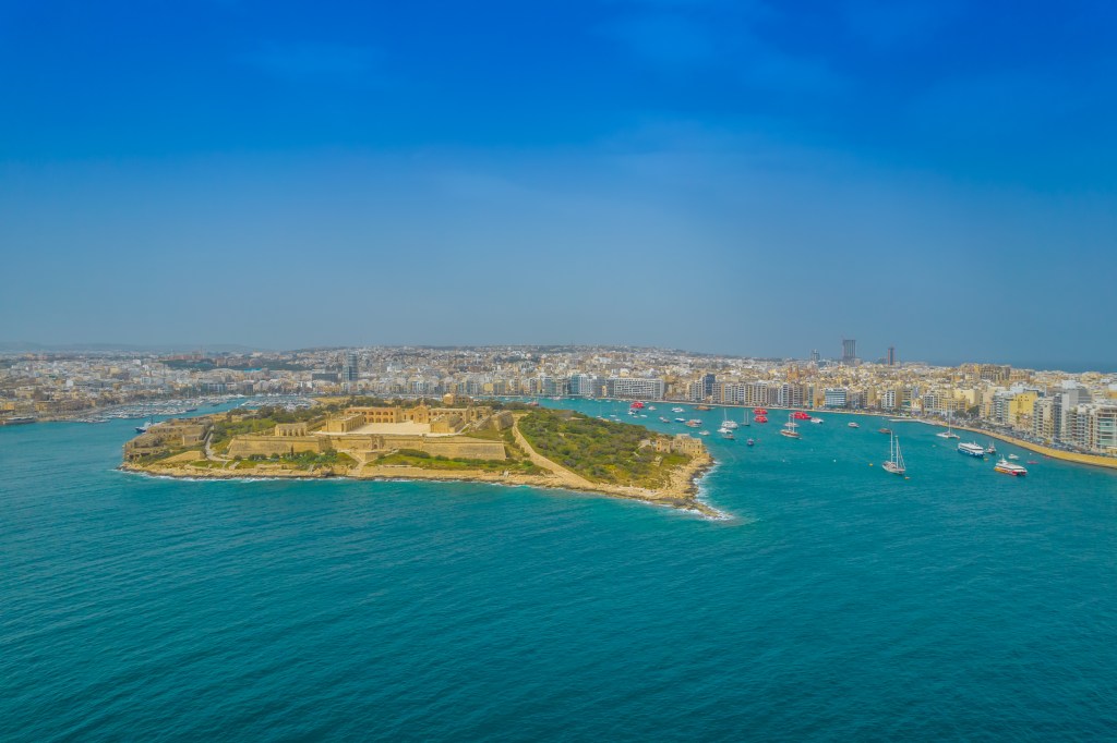 Luftaufnahme vom Wasser auf den Blick auf eine Insel vor den Ufern Maltas.