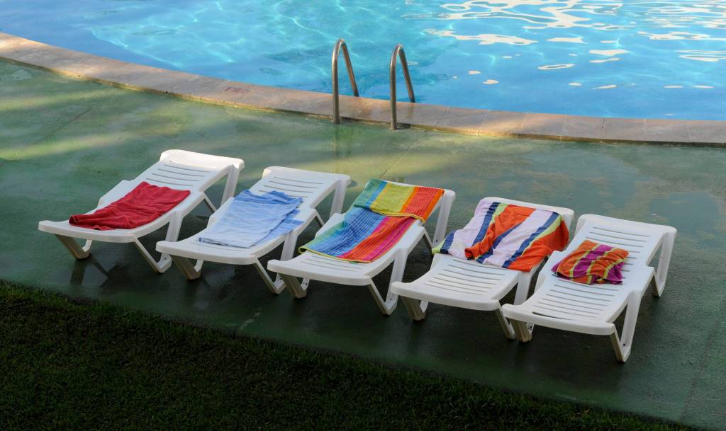 Auf fünf Sonnenliegen an einem Pool liegen Handtücher um zu signalisieren: Hier ist reserviert.