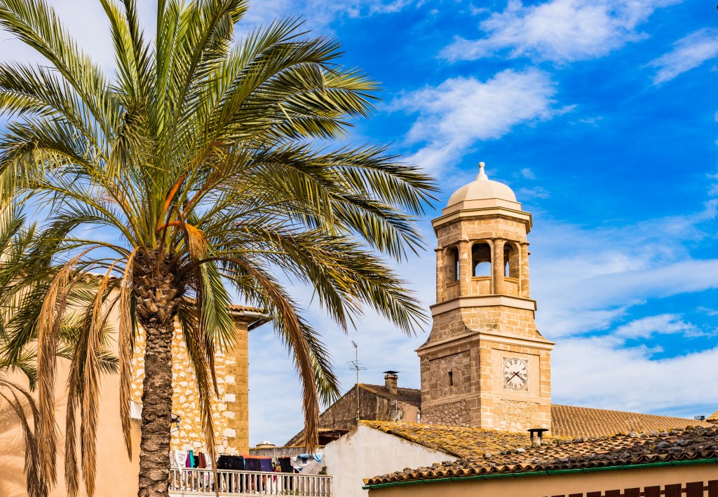 Die historische Pfarrkirche von Lloseta, umgeben von Palmen traditionellen Steinhäusern von Mallorca.