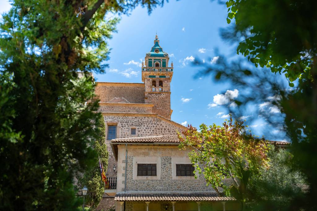 Turmspitze von Kirche hinter Bäumen.