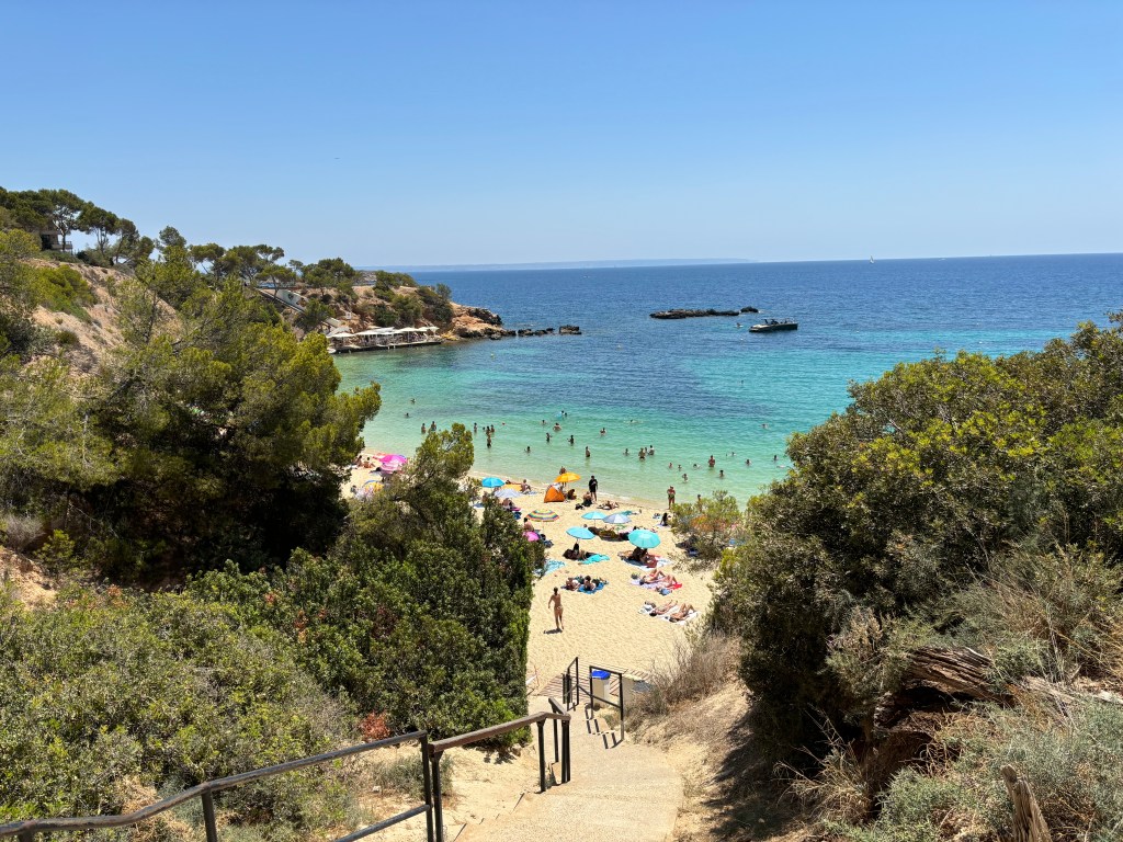 Menschen, die in der ruhigen Badebucht des Playa Oratori schwimmen und die Sonne genießen.