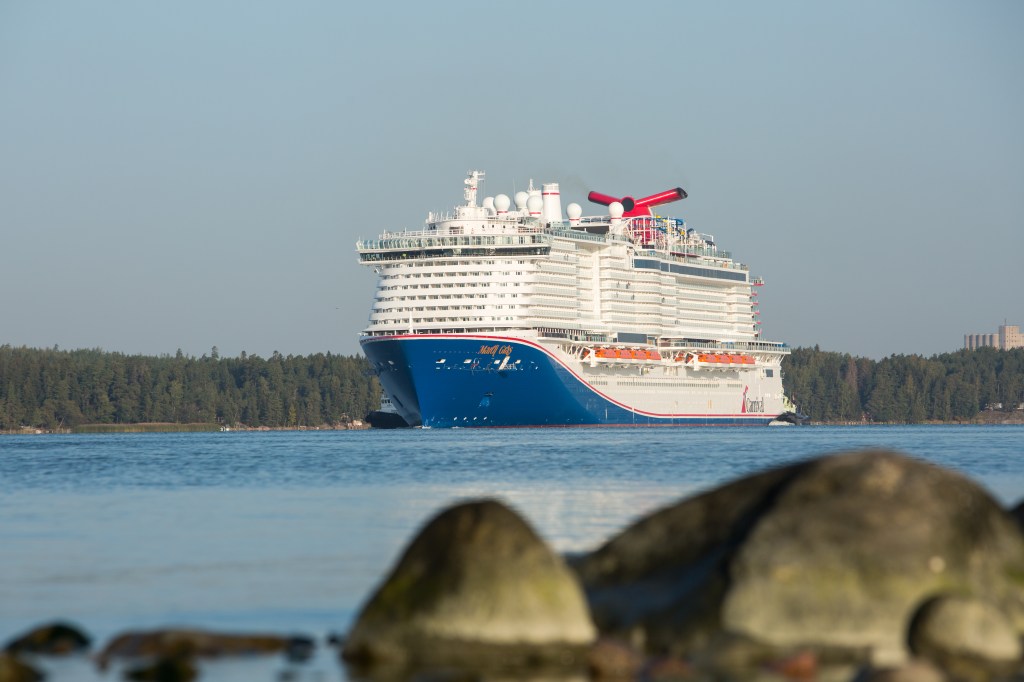 Kreuzfahrtschiff hinter Steinen eines Ufers