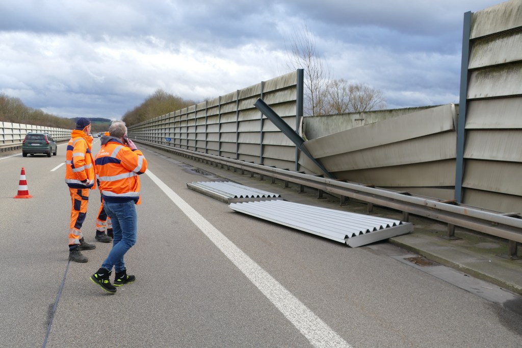 Auf der Autobahn A560 bei Hennef: stehen Arbeiter vor den Teilen einer  Lärmschutzwand, die der Sturm beschädigt hat.