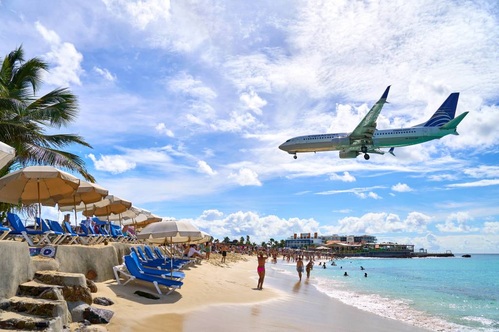 Flugzeug schwebt über Menschen am Strand