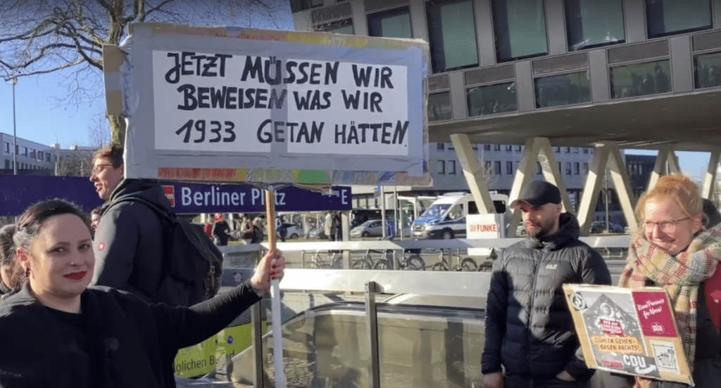 Eine Teilnehmerin der Demo in Essen zeigt ein Plakat, auf dem es heißt: "Jetzt müssen wir beweisen, was wir 1933 getan hätten."