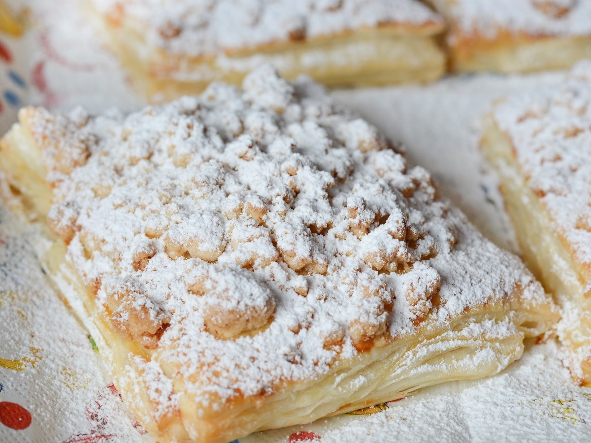 Prasselkuchen-Rezept: Ein StÃ¼ck Prasselkuchen mit Streuseln und Puderzucker, Nahaufnahme.