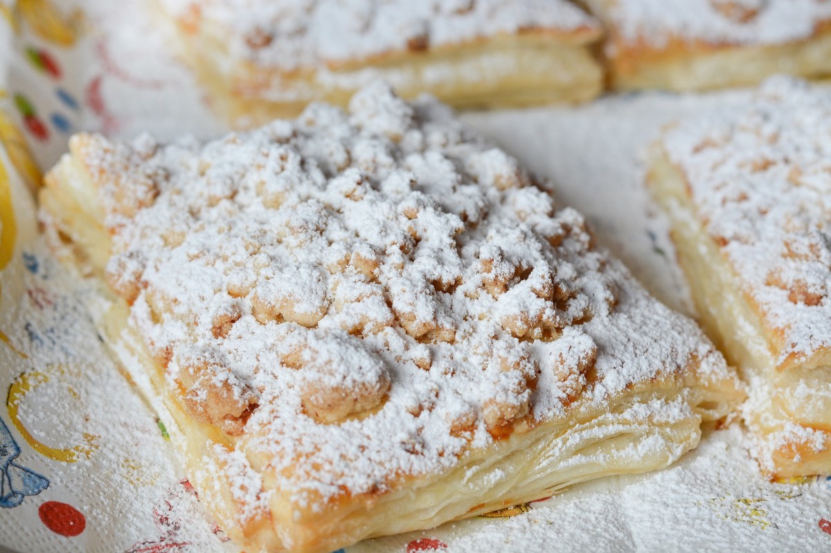 Prasselkuchen-Rezept: Ein StÃ¼ck Prasselkuchen mit Streuseln und Puderzucker, Nahaufnahme.