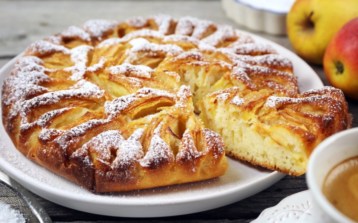 Ein ElsÃ¤sser Apfelkuchen mit Puderzucker auf einem Teller.